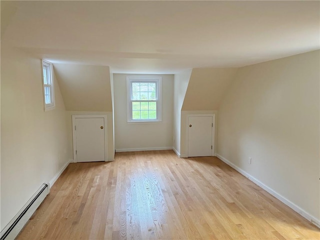 bonus room with light wood-type flooring, lofted ceiling, and a baseboard heating unit