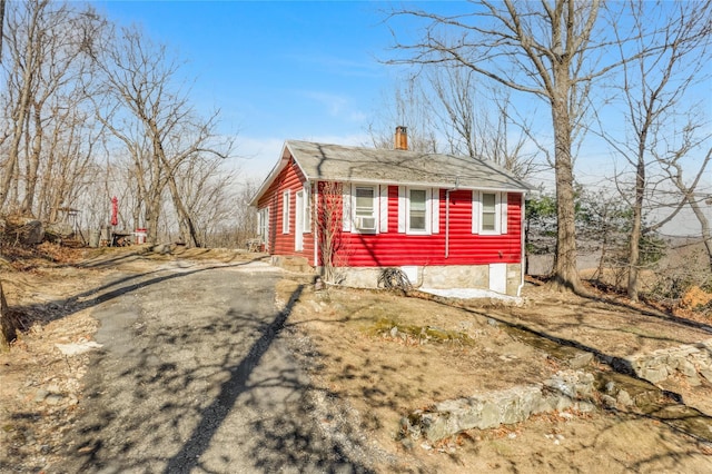 exterior space featuring cooling unit, a chimney, and driveway