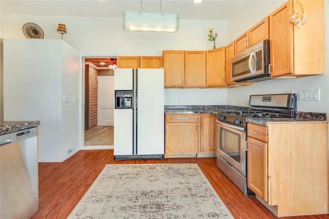 kitchen featuring dark stone countertops, recessed lighting, dark wood-style flooring, appliances with stainless steel finishes, and decorative light fixtures