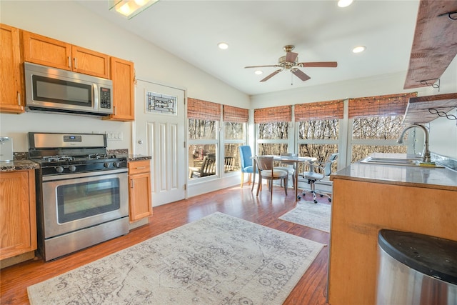 kitchen featuring a sink, wood finished floors, recessed lighting, stainless steel appliances, and vaulted ceiling