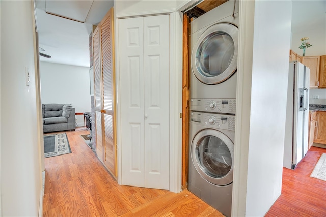 laundry area featuring light wood-style floors, laundry area, and stacked washer / dryer