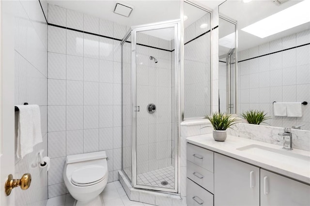 bathroom featuring walk in shower, vanity, toilet, and tile walls