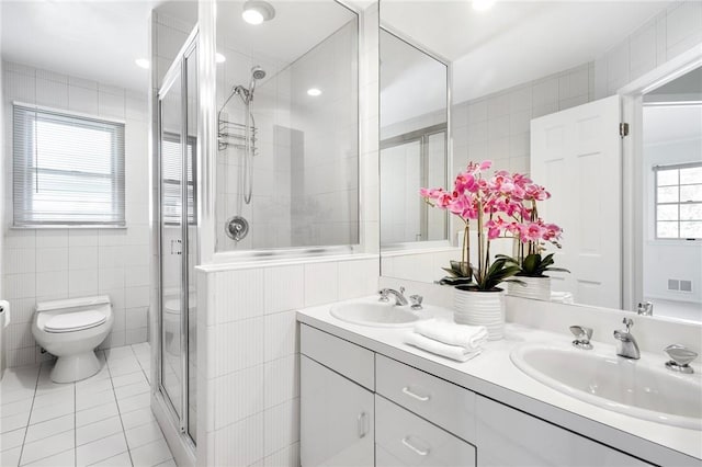 bathroom with tile patterned floors, vanity, tile walls, toilet, and a shower with shower door