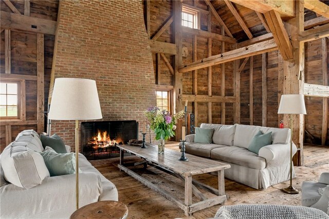 living room featuring a wealth of natural light, a fireplace, high vaulted ceiling, and brick wall