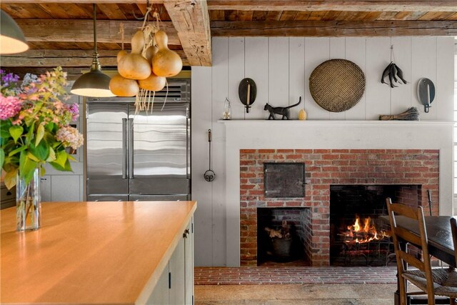 kitchen featuring pendant lighting, a brick fireplace, beam ceiling, high end fridge, and wood ceiling