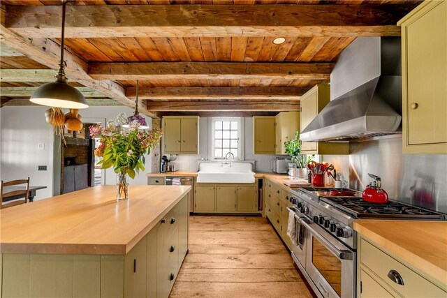 kitchen with beam ceiling, sink, wall chimney exhaust hood, and range with two ovens