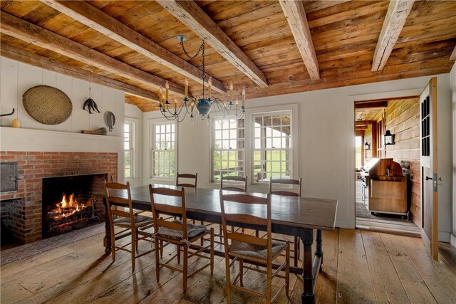 dining area with hardwood / wood-style floors, beam ceiling, wood ceiling, and a brick fireplace