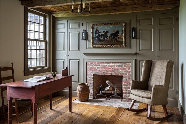 sitting room with hardwood / wood-style flooring, wooden ceiling, and a brick fireplace