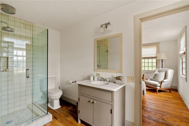 bathroom with hardwood / wood-style floors, vanity, toilet, and walk in shower