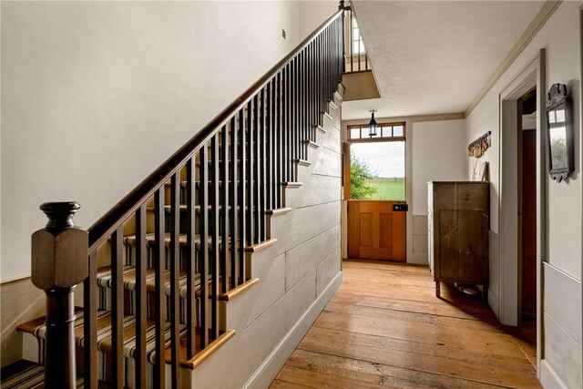 stairway with wood-type flooring and ornamental molding