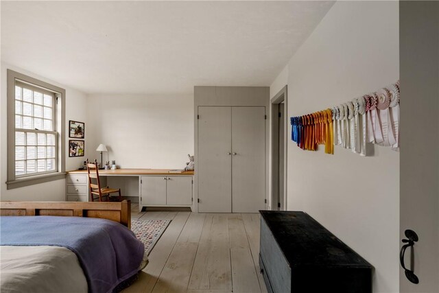 bedroom featuring a closet, built in desk, and light hardwood / wood-style floors