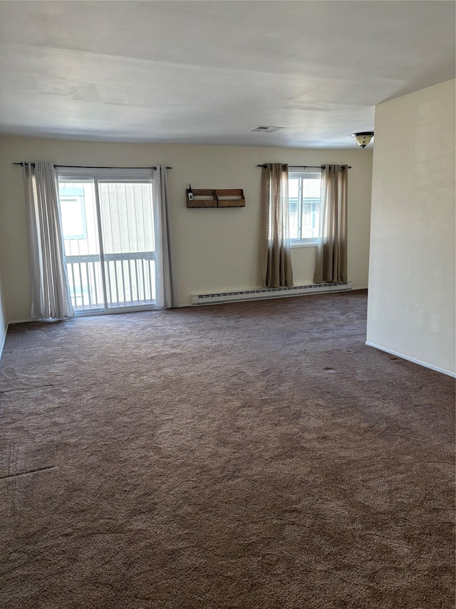 carpeted empty room featuring a baseboard heating unit