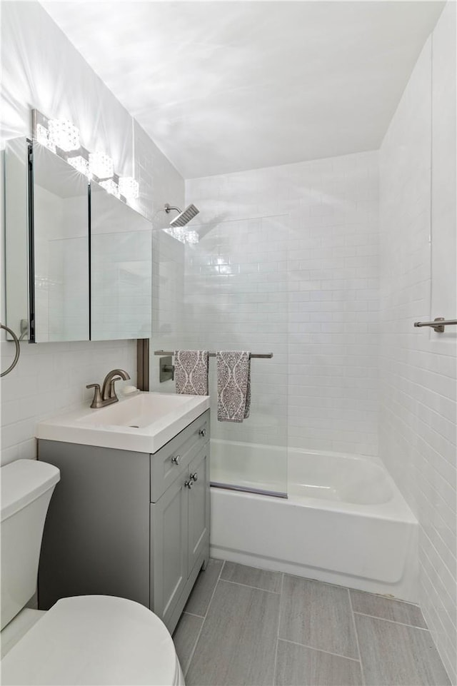 full bathroom with vanity, toilet, tile walls, and tiled shower / bath combo