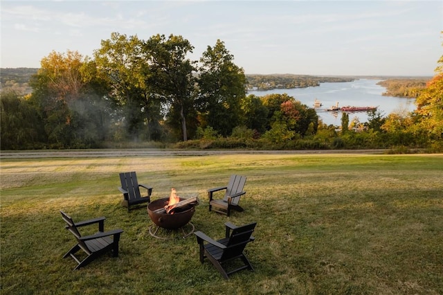 surrounding community featuring a water view, an outdoor fire pit, and a lawn