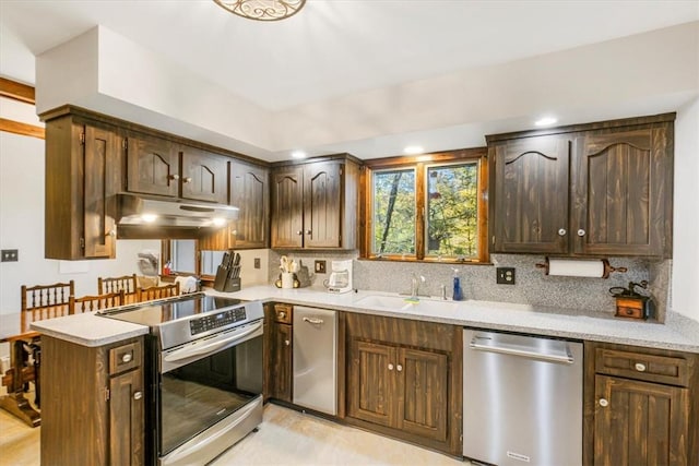 kitchen featuring kitchen peninsula, backsplash, dark brown cabinetry, stainless steel appliances, and sink