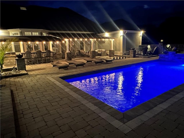 pool at twilight featuring a patio area