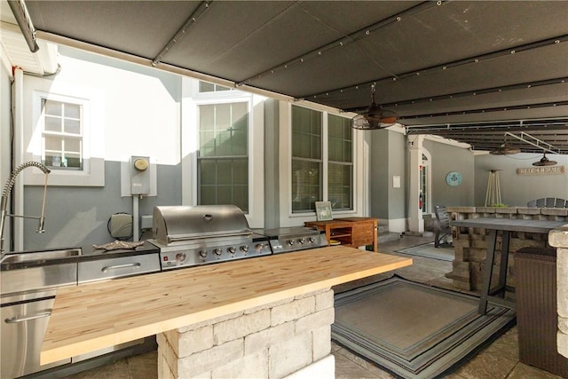 view of patio with grilling area, ceiling fan, an outdoor wet bar, and exterior kitchen