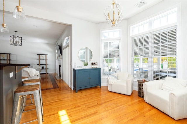 sitting room with a notable chandelier, light hardwood / wood-style floors, and a wealth of natural light