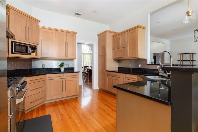 kitchen with kitchen peninsula, tasteful backsplash, stainless steel appliances, sink, and light hardwood / wood-style flooring