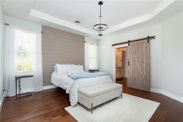 bedroom with a barn door, dark hardwood / wood-style flooring, and multiple windows