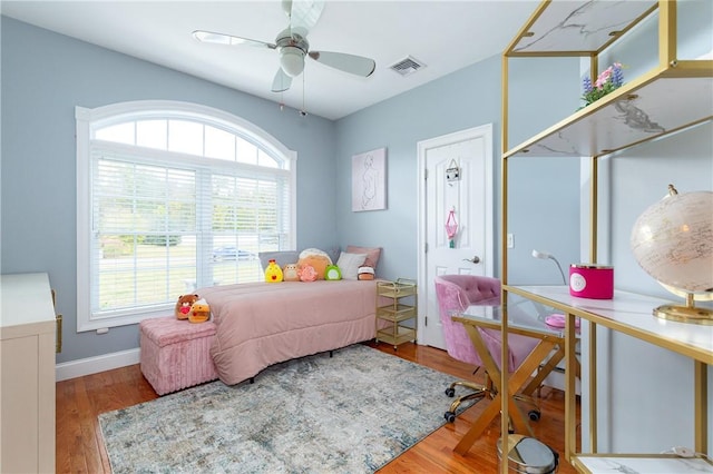 bedroom featuring hardwood / wood-style floors, ceiling fan, and multiple windows