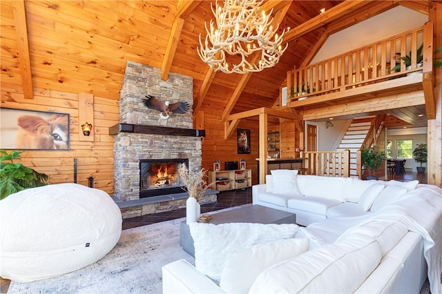 living room with wood walls, lofted ceiling with beams, a fireplace, a notable chandelier, and wood ceiling