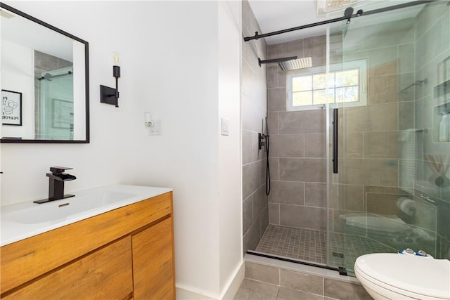 bathroom featuring tile patterned floors, vanity, a shower with shower door, and toilet