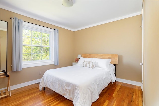 bedroom featuring ornamental molding and hardwood / wood-style flooring