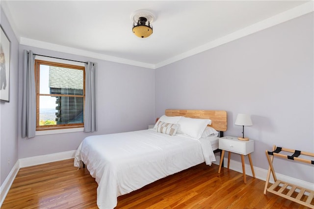 bedroom featuring wood-type flooring and ornamental molding