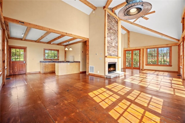 unfurnished living room with hardwood / wood-style floors, high vaulted ceiling, sink, ceiling fan, and a large fireplace