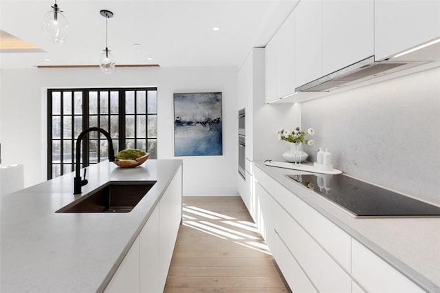 41 Richmondville Ave Unit 109, Call Listing Agent, CT 06880 - kitchen with a sink, black electric cooktop, light wood-style flooring, white cabinetry, and light countertops