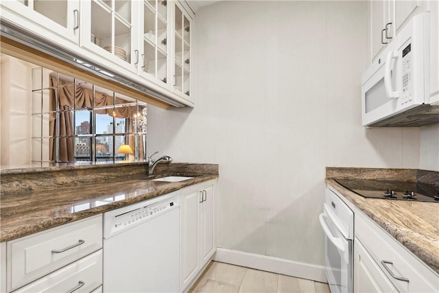 kitchen with white cabinets, white appliances, dark stone counters, and sink