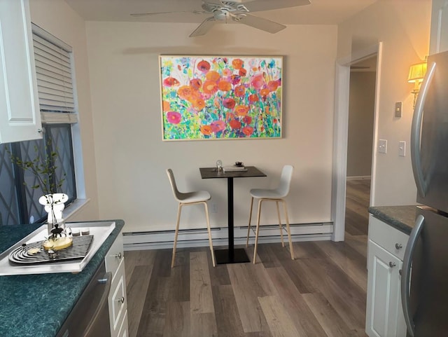 dining room featuring ceiling fan, baseboard heating, and dark wood-type flooring