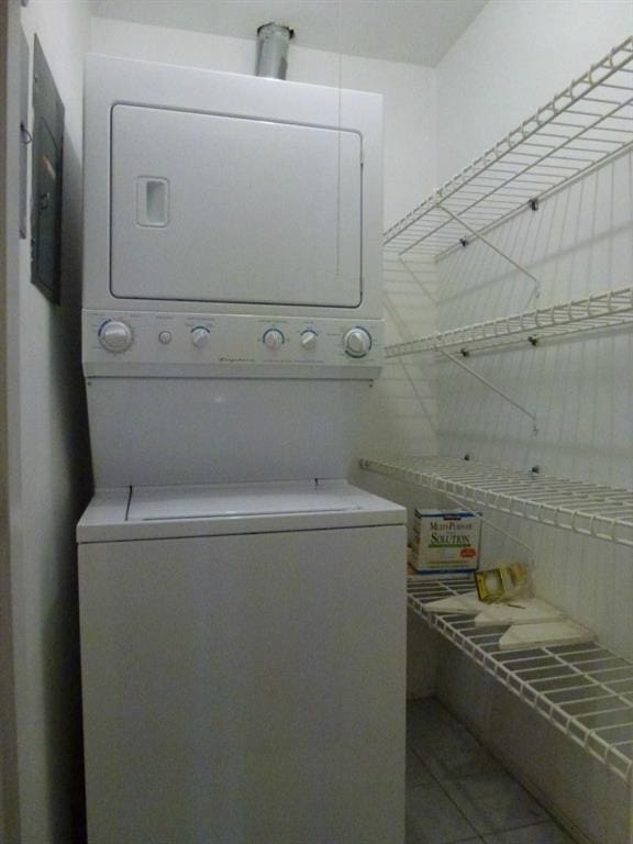 laundry room with stacked washer and dryer and tile patterned flooring