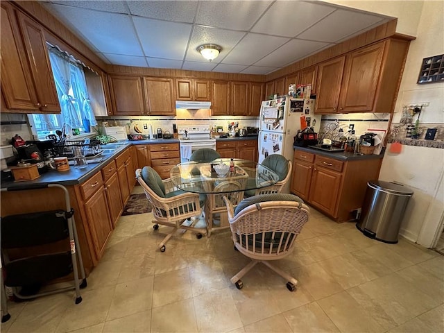 71 High St, Monticello, NY 12701 - kitchen with white range with electric stovetop, brown cabinetry, dark countertops, under cabinet range hood, and a drop ceiling