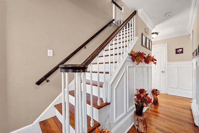 stairway with hardwood / wood-style floors and crown molding