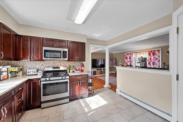 kitchen featuring ornate columns, light stone countertops, stainless steel appliances, a baseboard heating unit, and backsplash