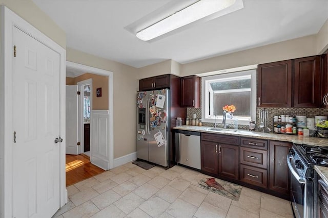 kitchen featuring backsplash, light stone countertops, sink, and stainless steel appliances