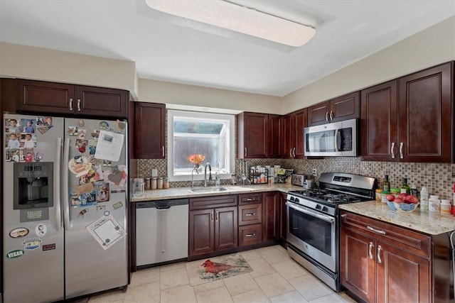 kitchen featuring sink, decorative backsplash, light tile patterned floors, appliances with stainless steel finishes, and light stone counters