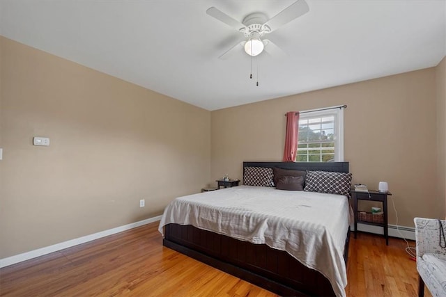 bedroom featuring hardwood / wood-style flooring, ceiling fan, and a baseboard heating unit