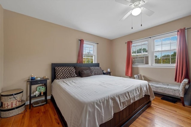 bedroom with wood-type flooring, multiple windows, and ceiling fan