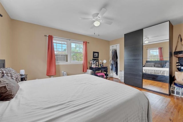 bedroom featuring ceiling fan, a closet, cooling unit, and light hardwood / wood-style floors