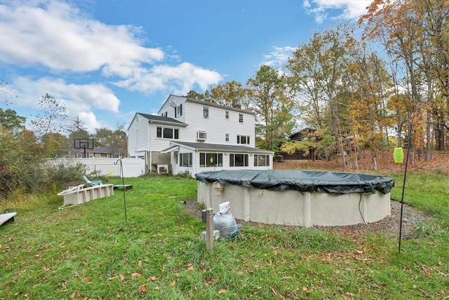 back of house with a covered pool and a lawn