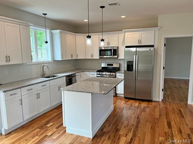 kitchen featuring white cabinetry, sink, pendant lighting, appliances with stainless steel finishes, and light wood-type flooring