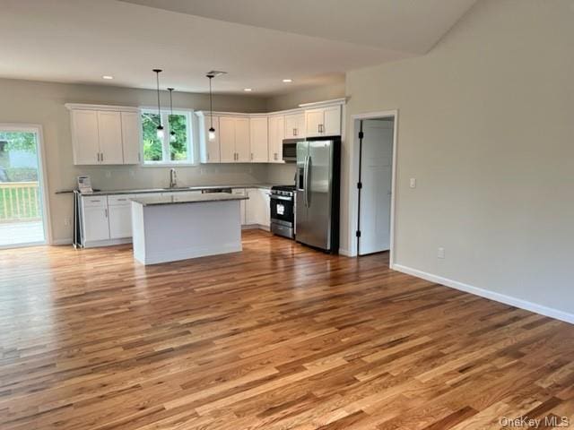 kitchen featuring a wealth of natural light, white cabinetry, stainless steel appliances, and hanging light fixtures