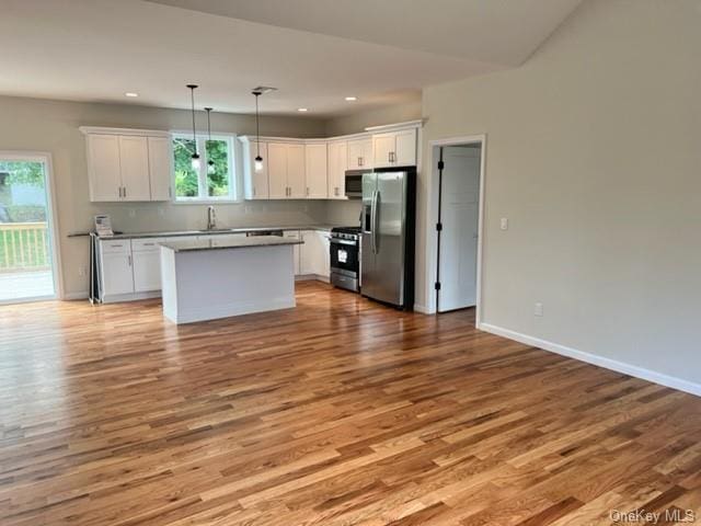 kitchen with a sink, white cabinets, light wood-style floors, appliances with stainless steel finishes, and a wealth of natural light