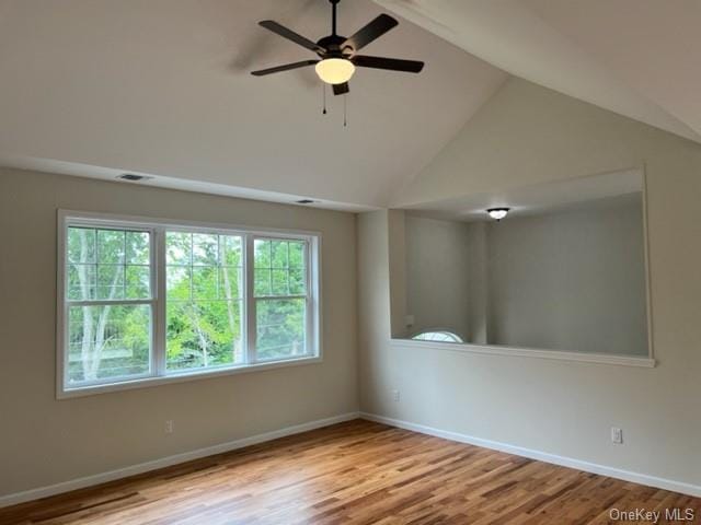 unfurnished room with wood finished floors, baseboards, visible vents, ceiling fan, and vaulted ceiling