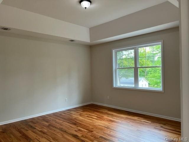 empty room featuring visible vents, baseboards, and wood finished floors