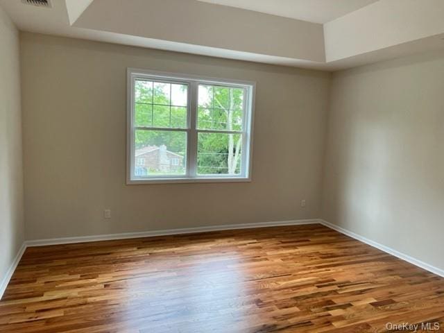 spare room with baseboards and wood finished floors