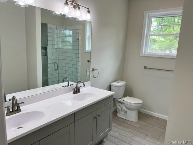 bathroom featuring a sink, toilet, a stall shower, and double vanity
